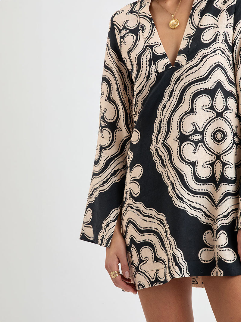 Close up on a Woman Standing wearing lemlem linen RAEY Column Dress  featuring  a custom-designed print inspired by ancient architectural patterns in cream and black colors