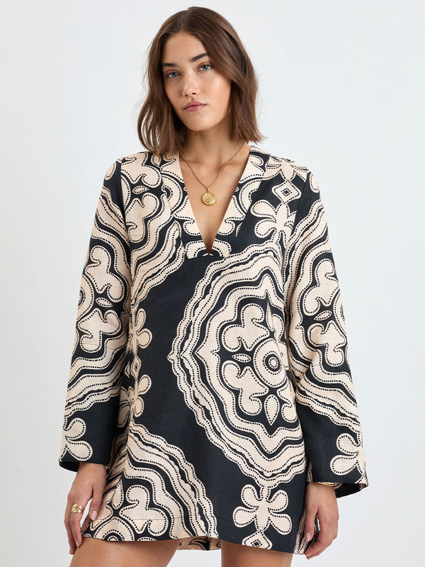 Woman Standing wearing lemlem linen RAEY Column Dress  featuring  a custom-designed print inspired by ancient architectural patterns in cream and black colors