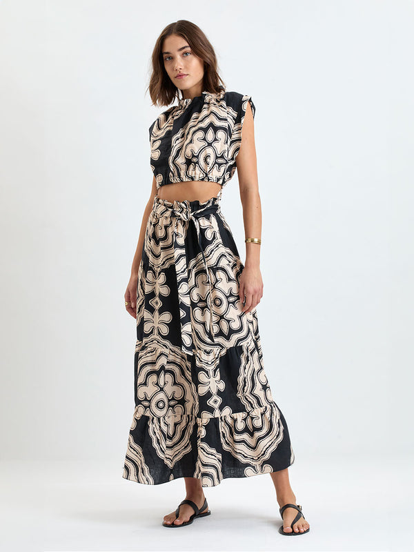 Woman wearing lemlem linen  SANAA Skirt featuring  a custom-designed print inspired by ancient architectural patterns in cream and black colors and a matching top