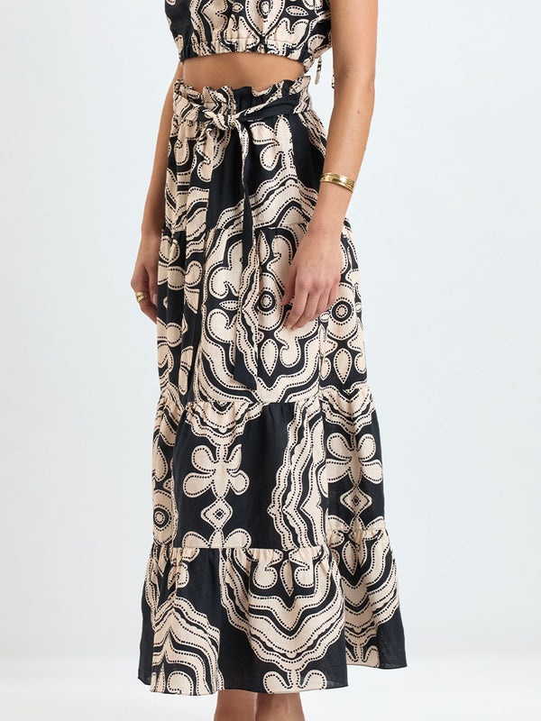 Woman wearing lemlem linen  SANAA Skirt featuring  a custom-designed print inspired by ancient architectural patterns in cream and black colors and a matching top