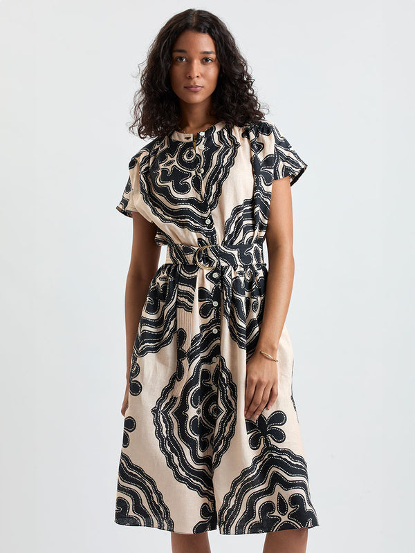 Woman Standing wearing lemlem HERAT Dress featuring ancient inspired pattern in black color on cream background