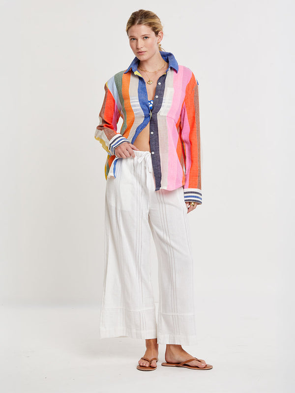 Woman wearing lemlem handwoven AISHA Shirt featuring bold, joyful stripe pattern in vibrant shades of blue, yellow, pink, orange, and green