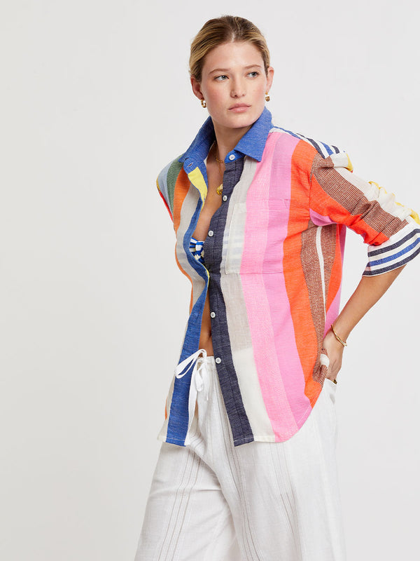 Woman wearing lemlem handwoven AISHA Shirt featuring bold, joyful stripe pattern in vibrant shades of blue, yellow, pink, orange, and green