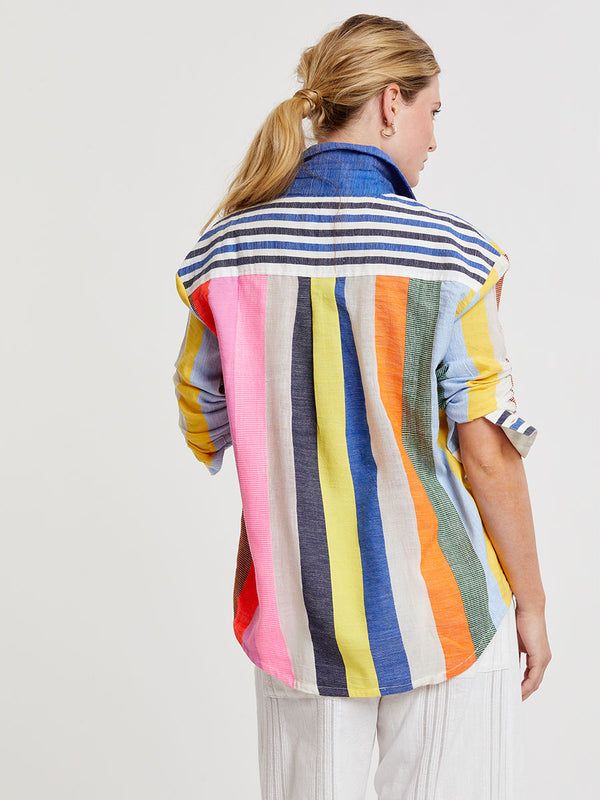 Woman wearing lemlem handwoven AISHA Shirt featuring bold, joyful stripe pattern in vibrant shades of blue, yellow, pink, orange, and green