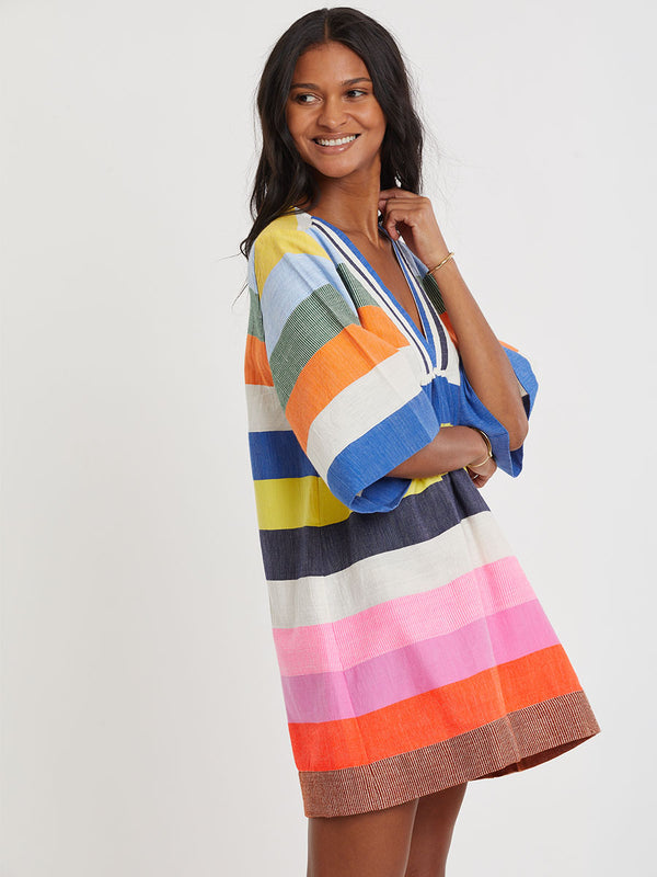 Woman wearing lemlem handwoven BELKIS Dress featuring bold, joyful stripe pattern in vibrant shades of blue, yellow, pink, orange, and green
