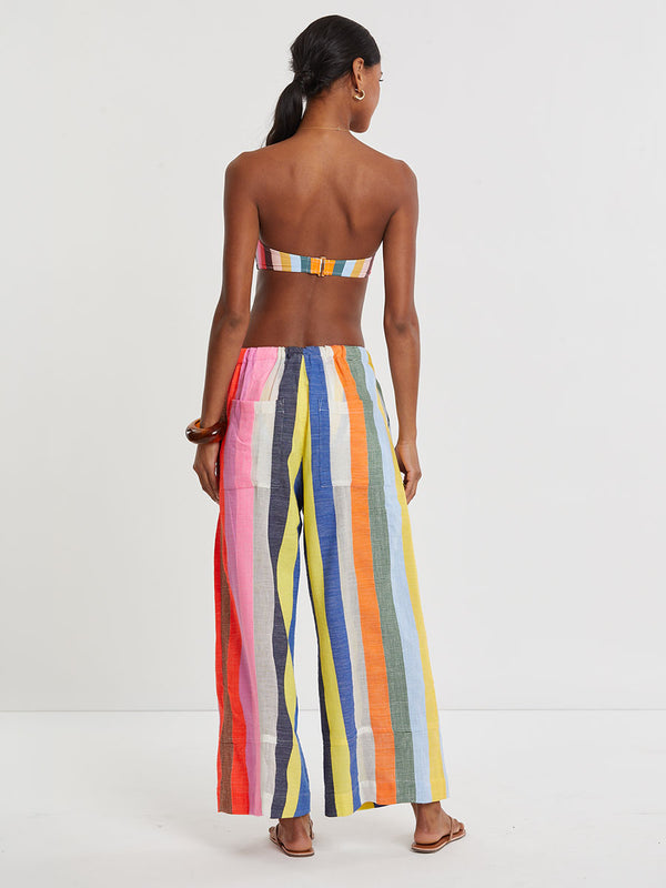 Woman wearing lemlem DESTA handwoven pants  featuring bold, joyful stripe pattern in vibrant shades of blue, yellow, pink, orange, and green