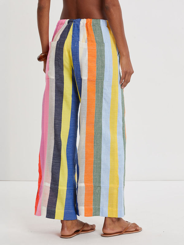 Woman wearing lemlem DESTA handwoven pants  featuring bold, joyful stripe pattern in vibrant shades of blue, yellow, pink, orange, and green