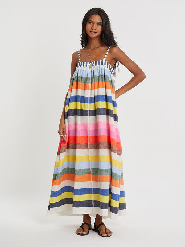 Woman wearing lemlem handwoven EDA Dress featuring bold, joyful stripe pattern in vibrant shades of blue, yellow, pink, orange, and green
