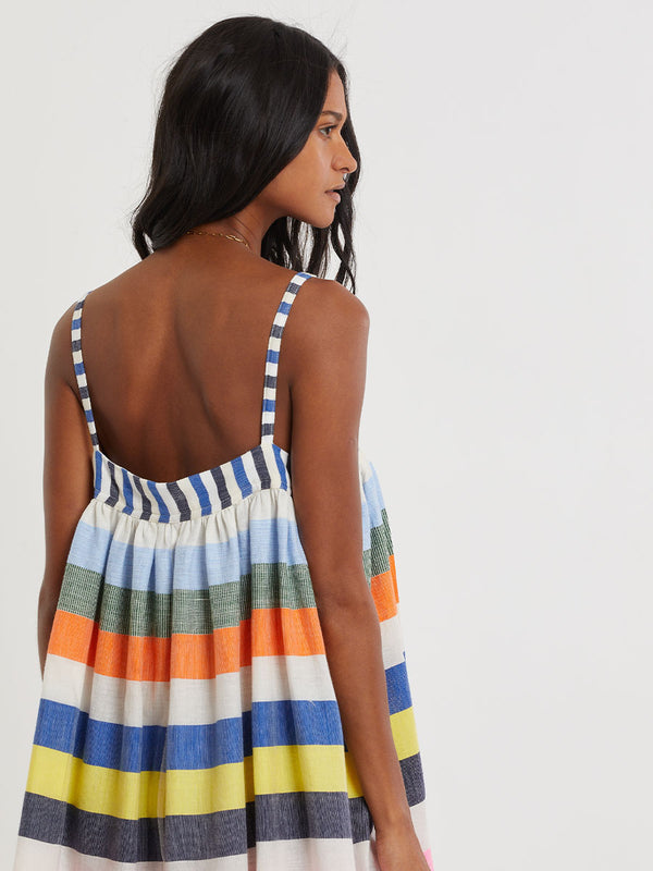 Woman wearing lemlem handwoven EDA Dress featuring bold, joyful stripe pattern in vibrant shades of blue, yellow, pink, orange, and green