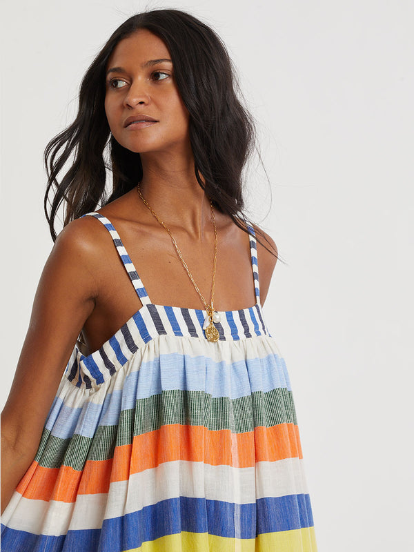 Woman wearing lemlem handwoven EDA Dress featuring bold, joyful stripe pattern in vibrant shades of blue, yellow, pink, orange, and green