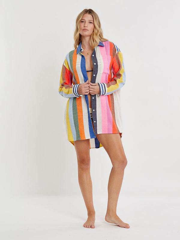 Woman wearing lemlem handwoven MARIAM Shirt featuring bold, joyful stripe pattern in vibrant shades of blue, yellow, pink, orange, and green