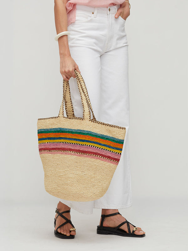 Person holding lemlem MIRA Raffia bag with colorful stripes on a white background