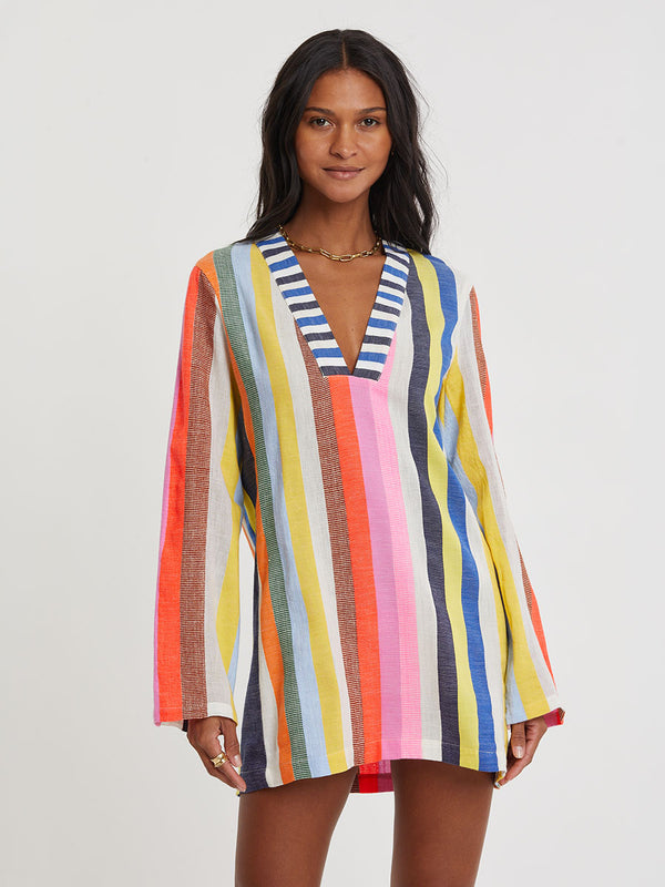 Woman wearing a colorful striped dress on a plain background