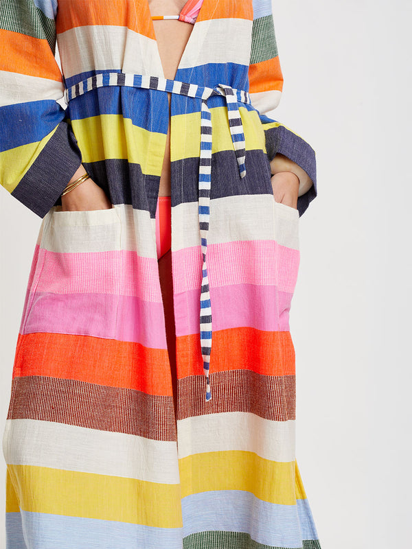 Woman wearing lemlem handwoven SHAWIT Long Robe featuring bold, joyful stripe pattern in vibrant shades of blue, yellow, pink, orange, and green