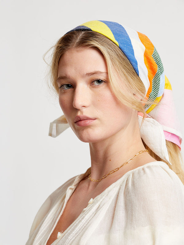 Woman wearing a colorful  lemlem DANA Bandana on a white backgroung