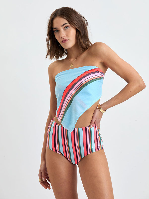 Woman wearing lemlem DANA Bandana featuring color block stripe pattern in white on sky blue background as a top and matching bikini bottom