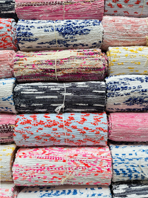Shot of assorted rolled lemlem handwoven rugs 
