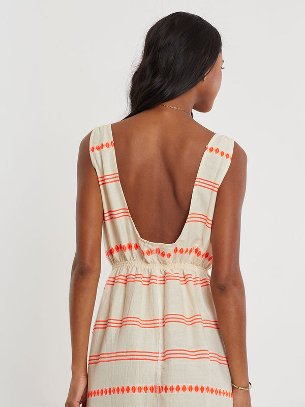 Woman Standing wearing lemlem handwoven MELAT Dress featuring intricate electric orange toned Tibeb pattern on a cream biscuit background.