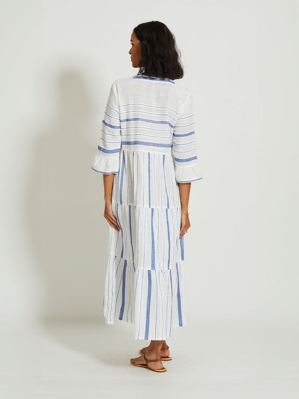 Back of a Woman Standing Wearing lemlem HAWI | Flutter Dress featuring crisp white fabric woven with diagonal dotted stripes in bright blue and a subtle textured weave