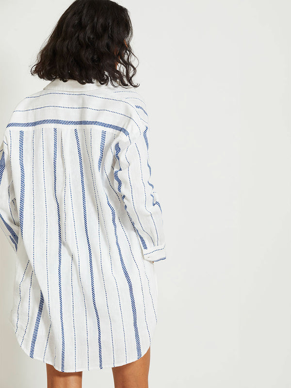 Back of a Woman Standing Wearing lemlem MARIAM | Shirt Dress featuring crisp white fabric woven with diagonal dotted stripes in bright blue and a subtle textured weave