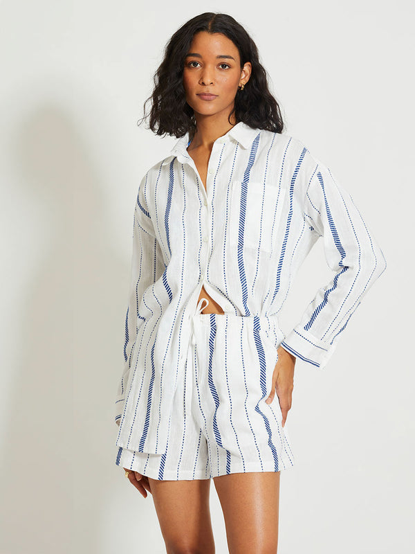 Woman Standing Wearing lemlem MARIAM | Shirt Dress featuring crisp white fabric woven with diagonal dotted stripes in bright blue and a subtle textured weave