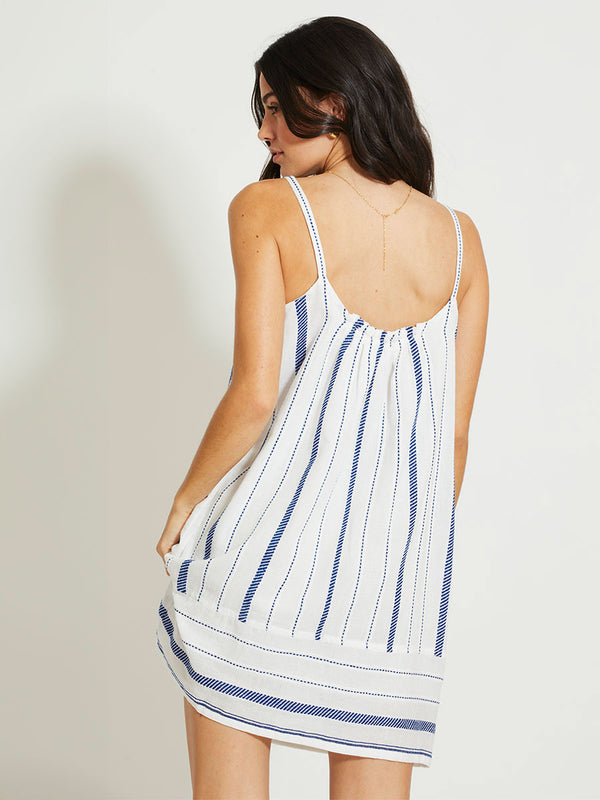 Back of a Woman Standing Wearing lemlem ZINA | Swing Dress featuring crisp white fabric woven with diagonal dotted stripes in bright blue and a subtle textured weave