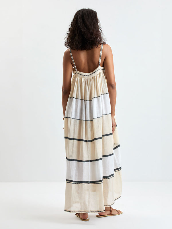 Back of a Woman standing wearing lemlem handwoven EDA Dress featuring  refined palette of crisp white, soft cream, and deep black