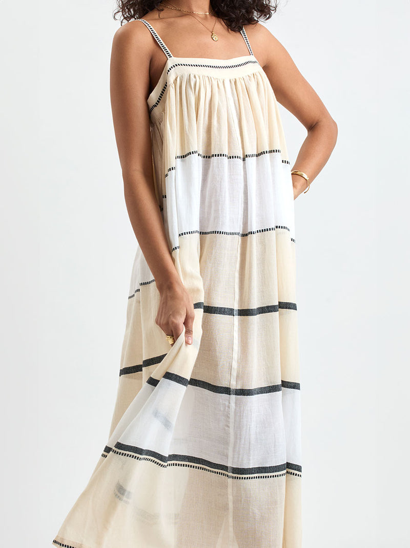 Close up on a Woman standing wearing lemlem handwoven EDA Dress featuring  refined palette of crisp white, soft cream, and deep black