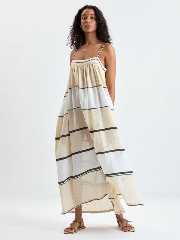 Woman standing wearing lemlem handwoven EDA Dress featuring  refined palette of crisp white, soft cream, and deep black