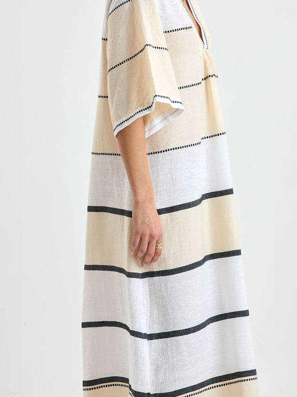 Close up on a Woman standing wearing lemlem handwoven EDNA Dress featuring  refined palette of crisp white, soft cream, and deep black