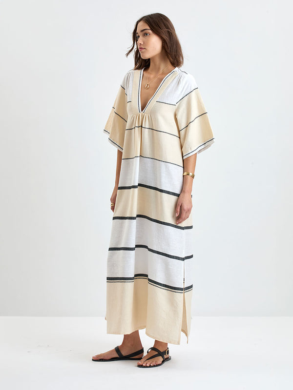 Woman standing wearing lemlem handwoven EDNA Dress featuring  refined palette of crisp white, soft cream, and deep black