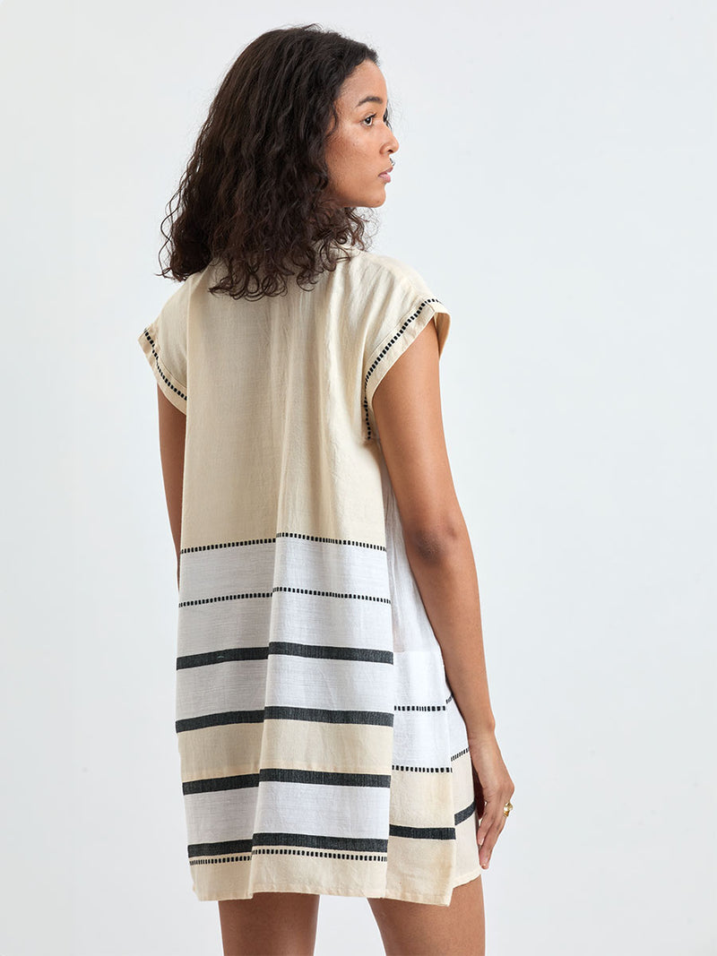 Back of a Woman standing wearing lemlem handwoven ELINA Caftan featuring  refined palette of crisp white, soft cream, and deep black