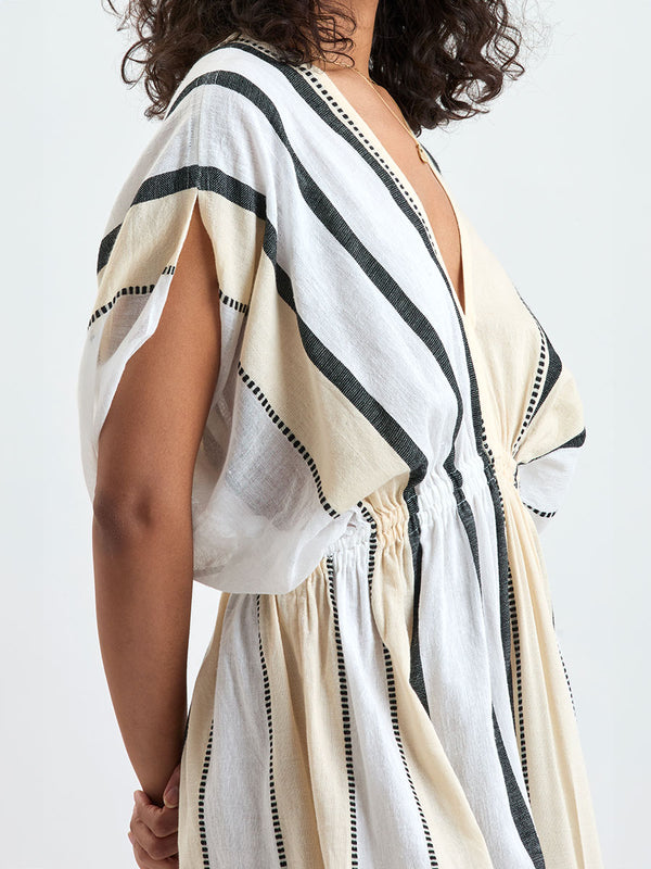 Close up on a Woman standing wearing lemlem handwoven LEILA Dress featuring  refined palette of crisp white, soft cream, and deep black