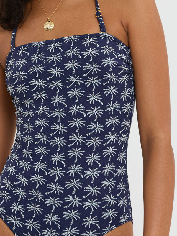 Close up on a Woman Standing Wearing lemlem DINHA One Piece featuring ivory palm tree motifs set against a rich navy background