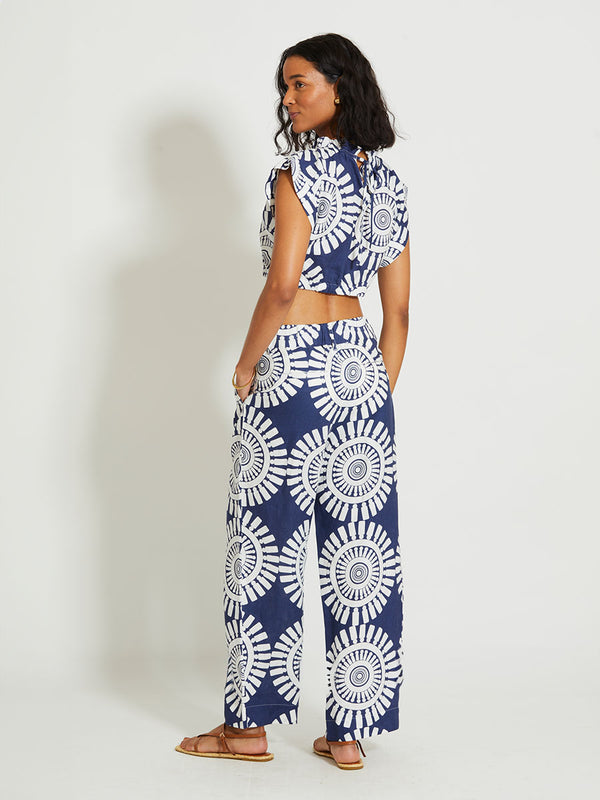 Back of a Woman Standing Wearing lemlem DIARRA | Trousers Featuring a bold geometric medallion pattern on navy background, inspired by traditional Tibeb motifs.