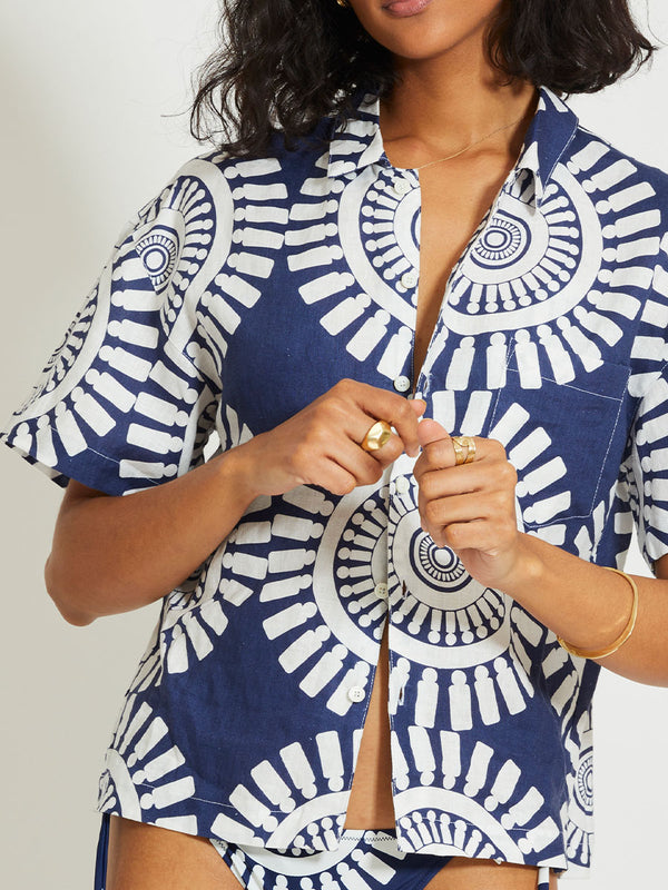 Close up on a Woman Standing Wearing lemlem TUULI | Cabana Shirt Featuring a bold geometric medallion pattern on navy background, inspired by traditional Tibeb motifs.