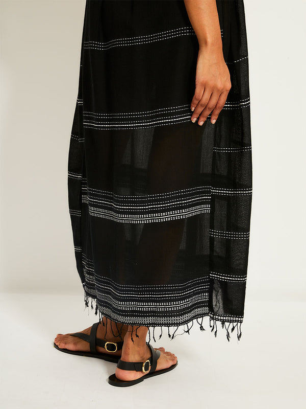 close up on legs of a woman standing wearing the Leliti Slip Dress in Black with white stitching allover.