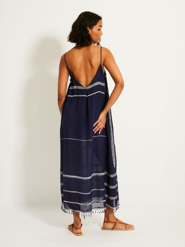 Back view of a woman standing wearing the Nunu Long Slip Dress in navy blue featuring white stripes and graphic lines.