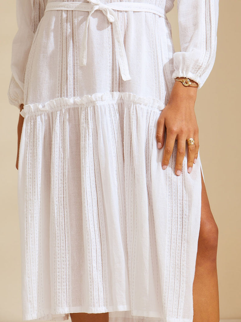 Close up view of the legs of a woman wearing a white Abira Poet Shirt Dress with stitches of silver lurex