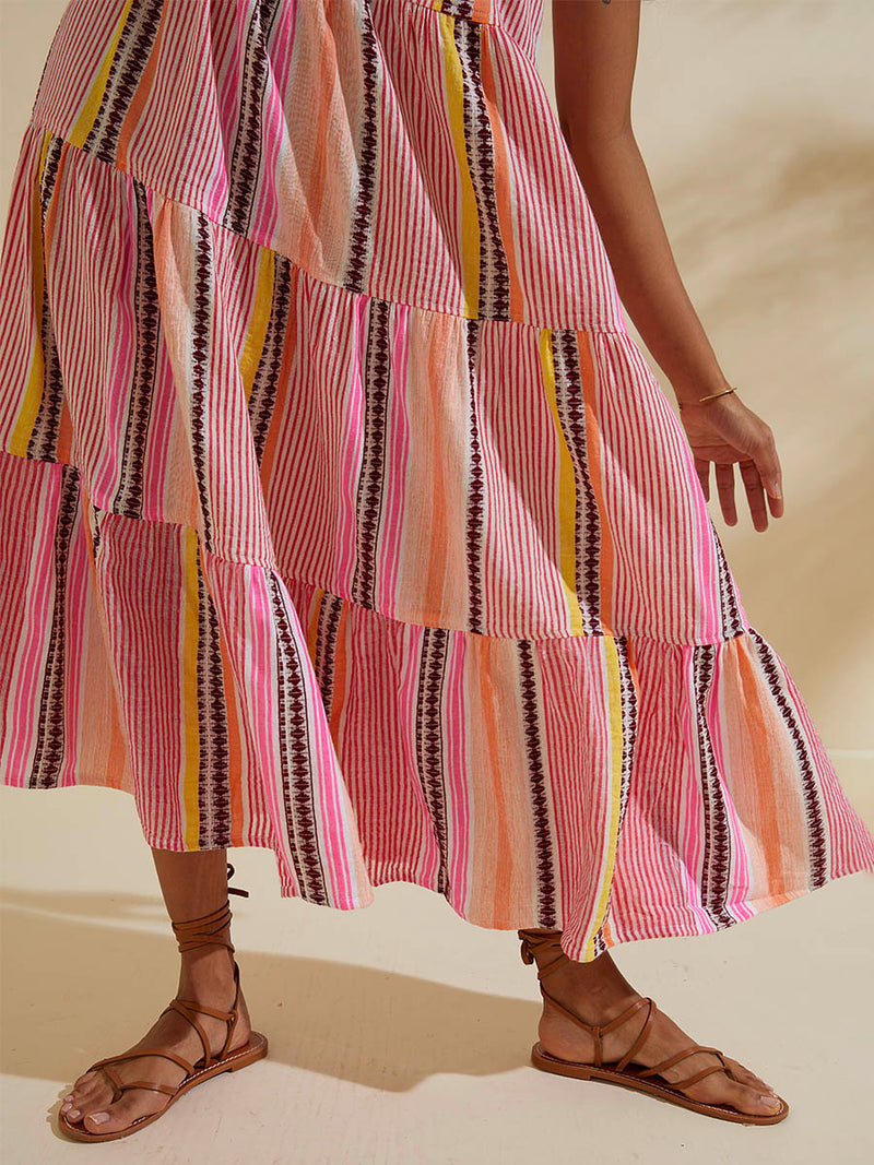 Close up on the legs of a woman wearing the Cirq Cascade Dress featuring pink, orange and yellow stripes and signature Tibeb design in burgundy bands.