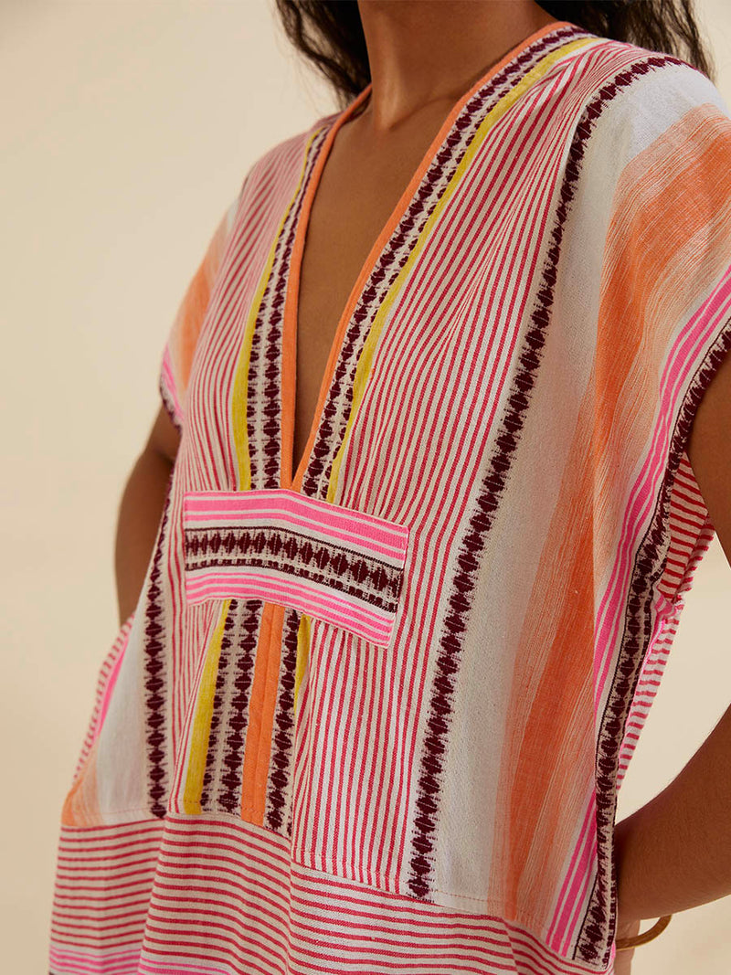 Close up on the chest of a woman wearing the Cirq Long Caftan Dress featuring pink, orange and yellow stripes and signature Tibeb design in burgundy bands.