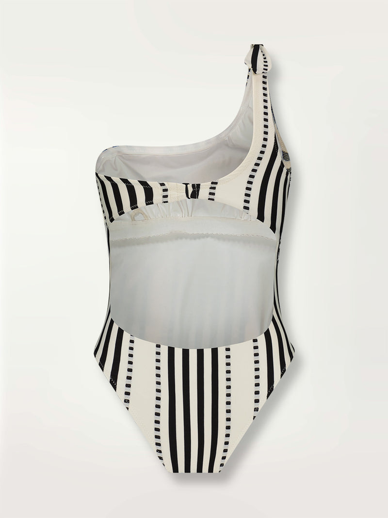 Product shot of the back the Eshe One Shoulder One Piece featuring architectural and textured black stripes and dotted lines on an off white background.