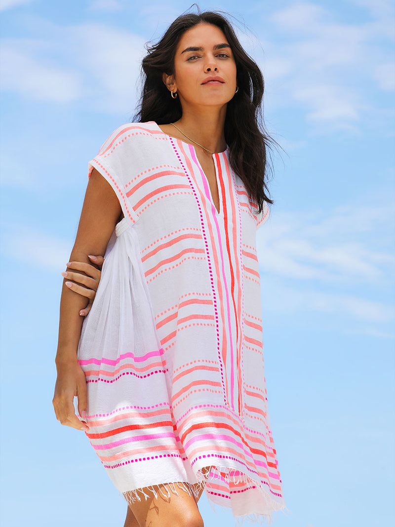 A woman standing wearing the Eshe Caftan Dress in pink featuring pink stripes and dots pattern.