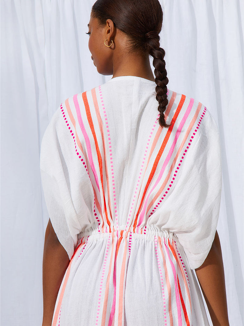 The back view of a woman standing wearing the Eshe Plunge Neck Dress in pink featuring pink stripes and dots pattern.