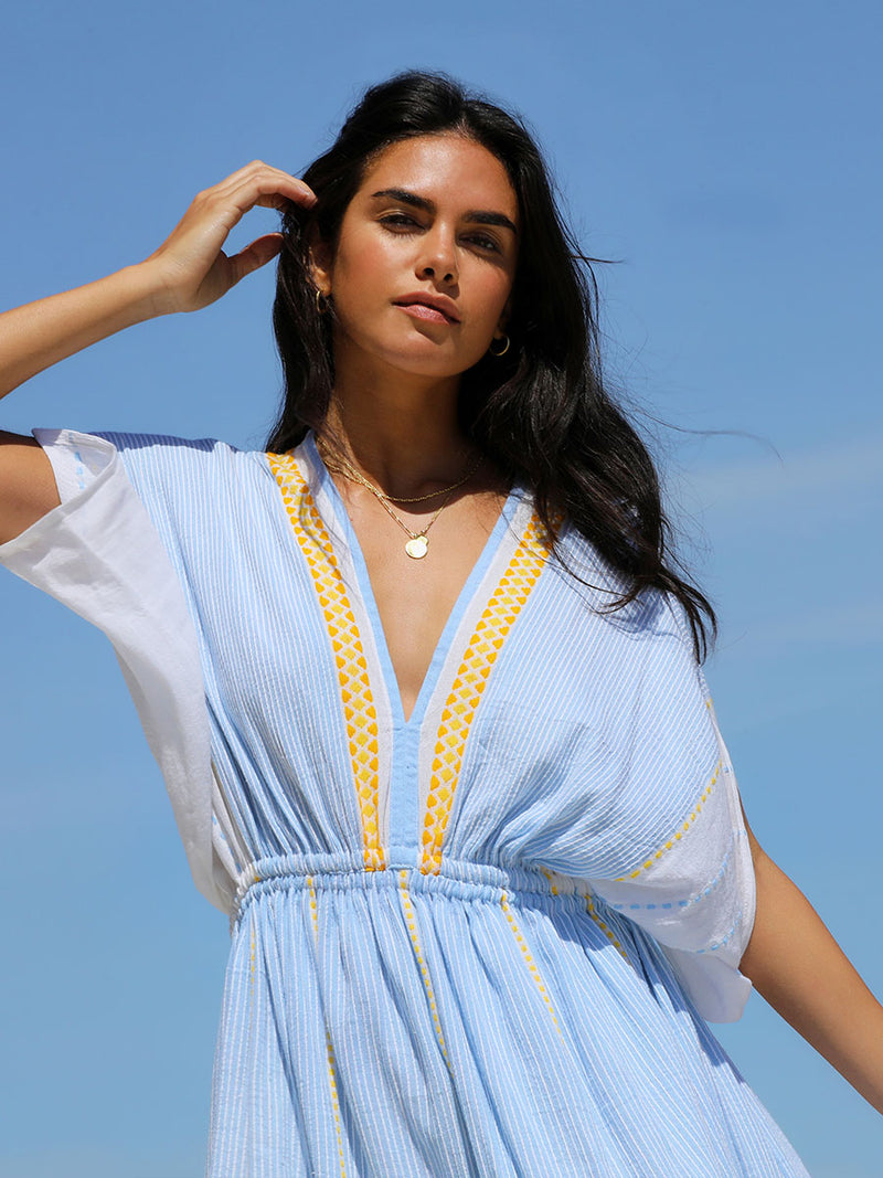 The close up view of a woman wearing the Jemari Plunge Neck Dress in sky blue featuring yellow and orange diamond patterns