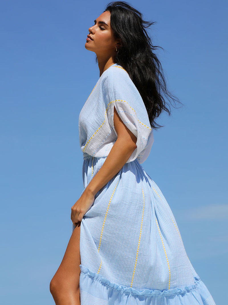 The side view of a woman wearing the Jemari Plunge Neck Dress in sky blue featuring yellow and orange diamond patterns