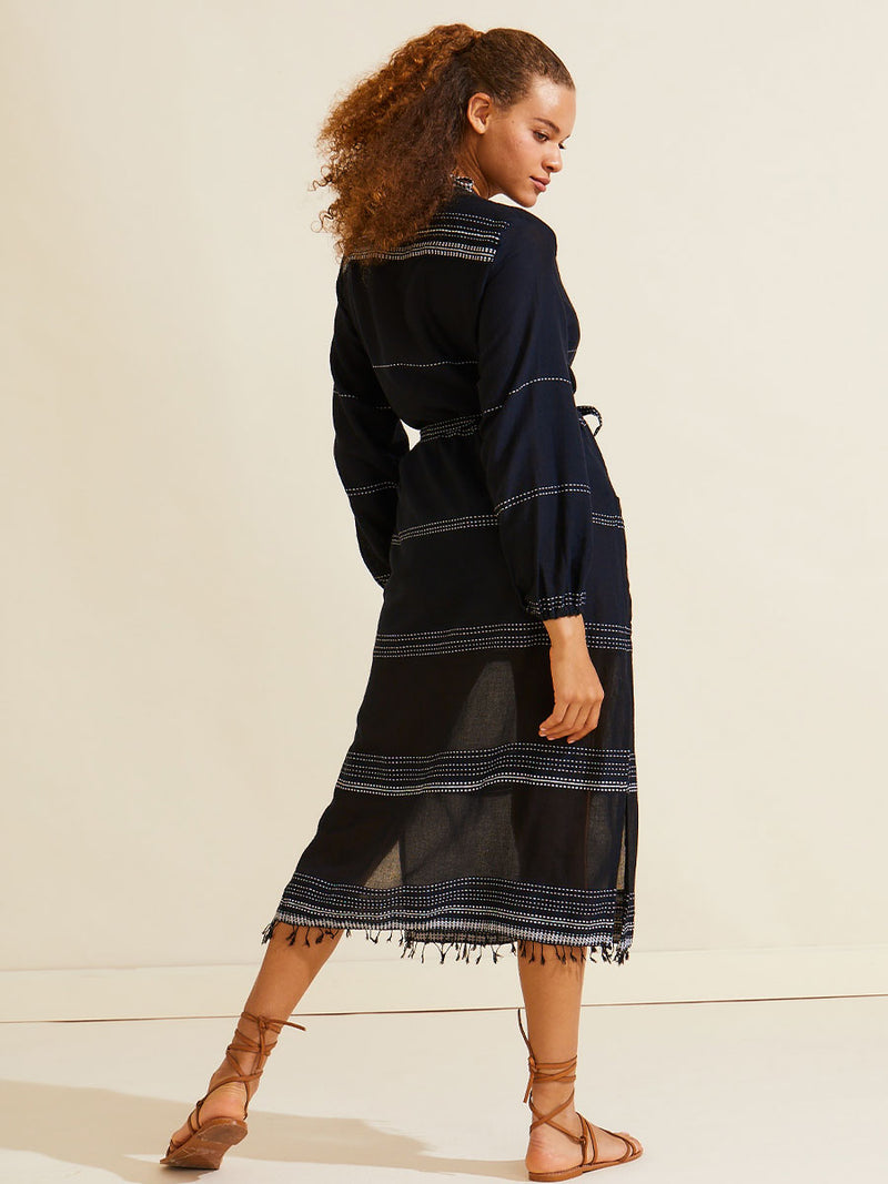 Back view of a Woman standing wearing the Leliti Long Robe in black with white stitching allover and matching waist tie.