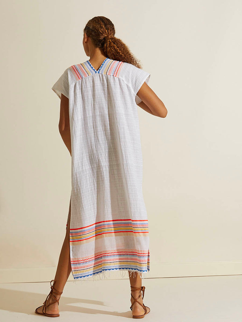 Back view of a woman wearing the Bekah Long Caftan Dress featuring 10 tutti frutti colors embroidered on a white background.  