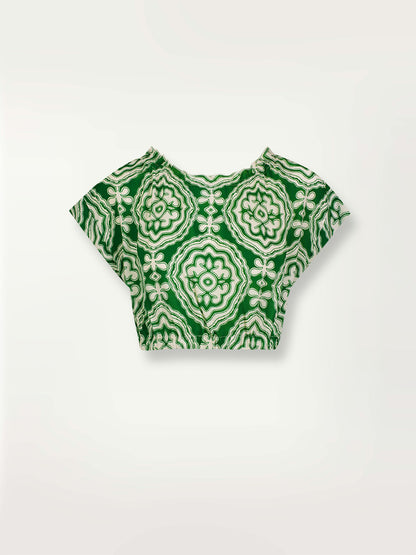 Product shot of the Medallion Ruched Crop Top featuring architectural white patterns on a deep green background.