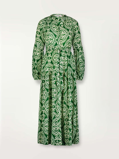 Product shot of the Medallion Peasant Dress featuring architectural white patterns on a deep green background.